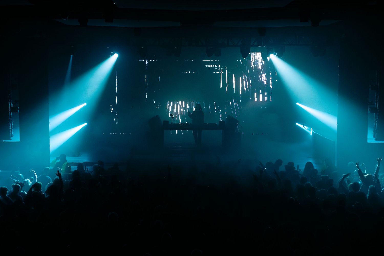 Concert stage illuminated with vibrant blue lights creating a dramatic silhouette effect during a live performance.