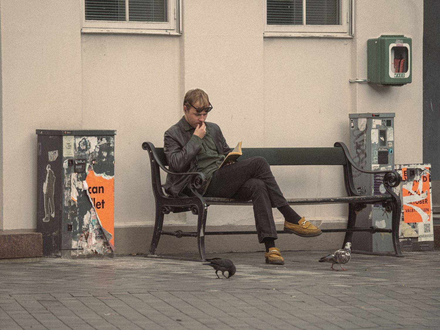 People sitting on benches outside a modern building with shopping bags nearby.