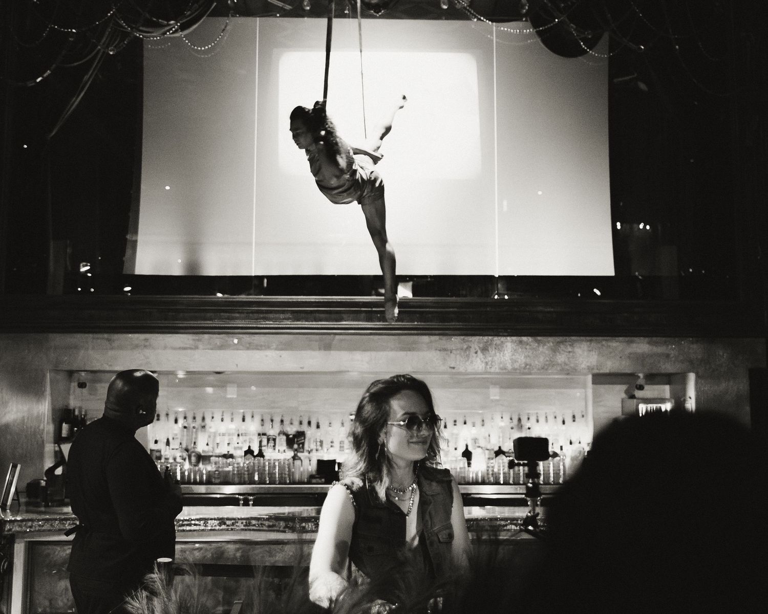 Artistic sequence showing movement and dance against a backlit window in a bar setting.