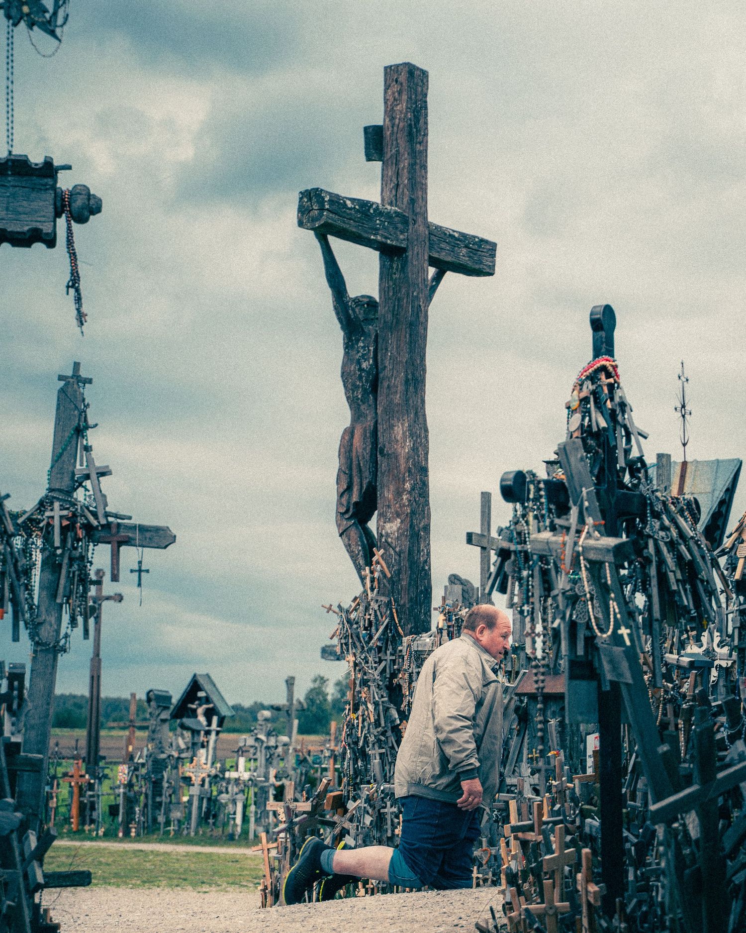 Hill of Crosses pilgrimage site in Lithuania showing wooden crosses against cloudy sky.