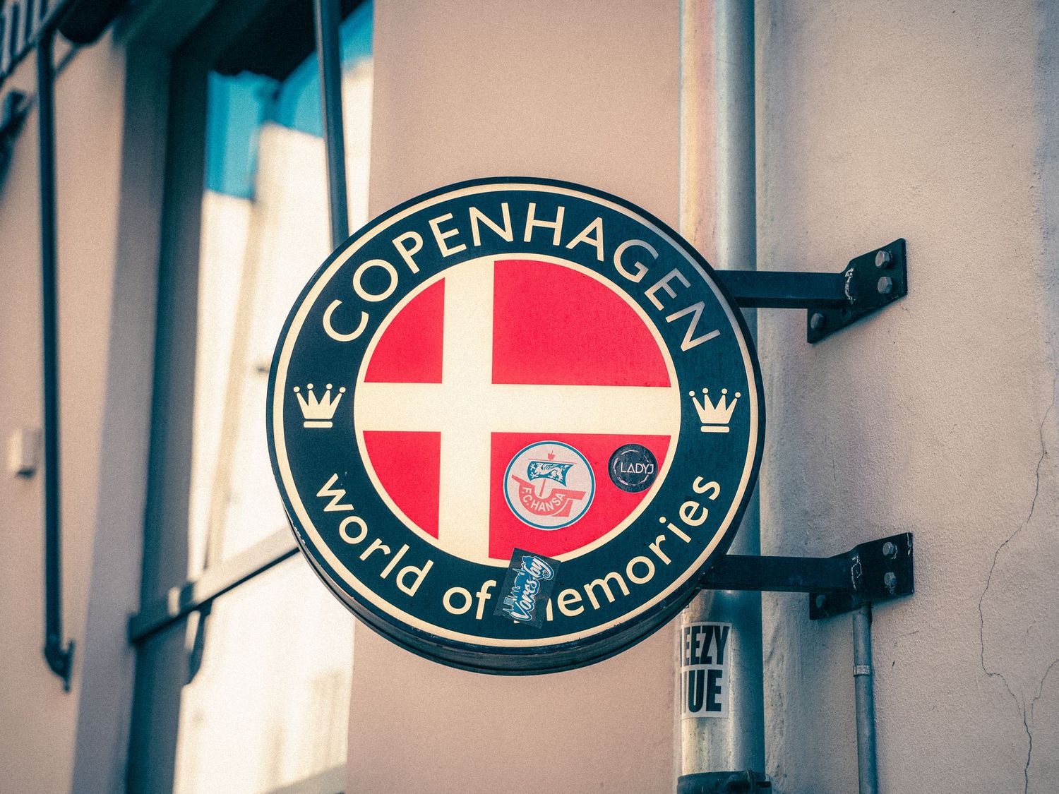 Copenhagen beer signs and logos mounted on a white wall in an establishment.
