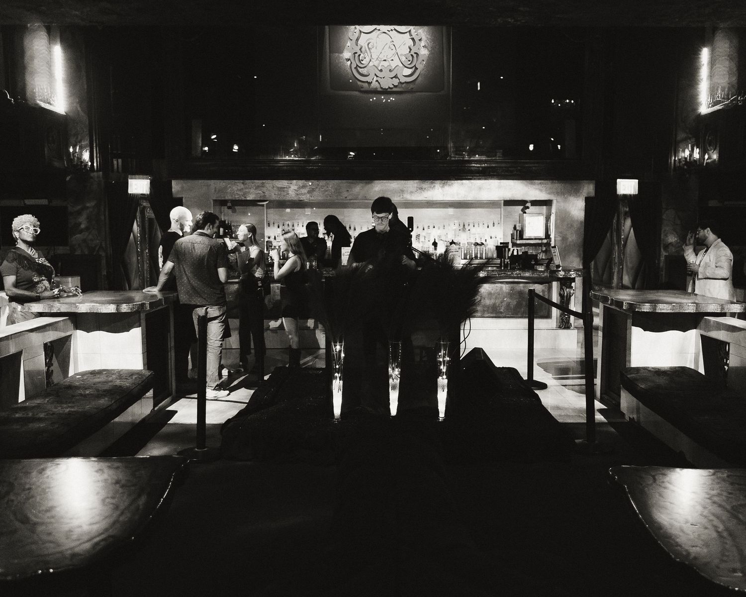 Black and white nightclub interior with moody lighting and dark silhouettes of patrons.