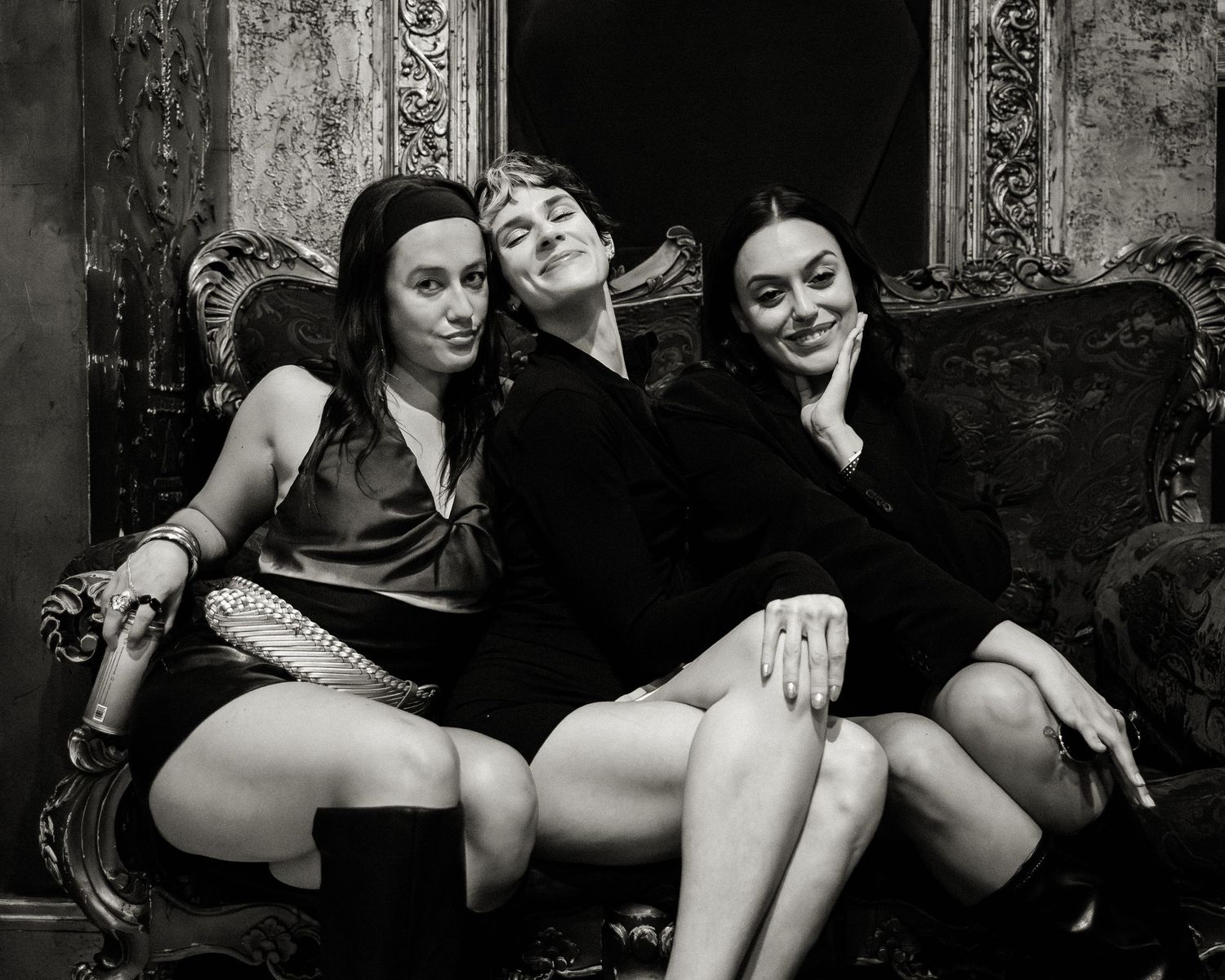 Artistic black and white photo of people posing on antique furniture.