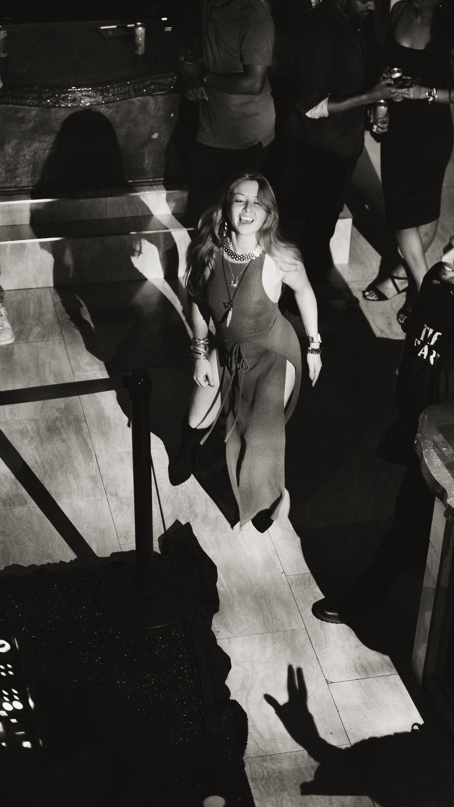People dancing on a nightclub floor with dramatic lighting and shadows.