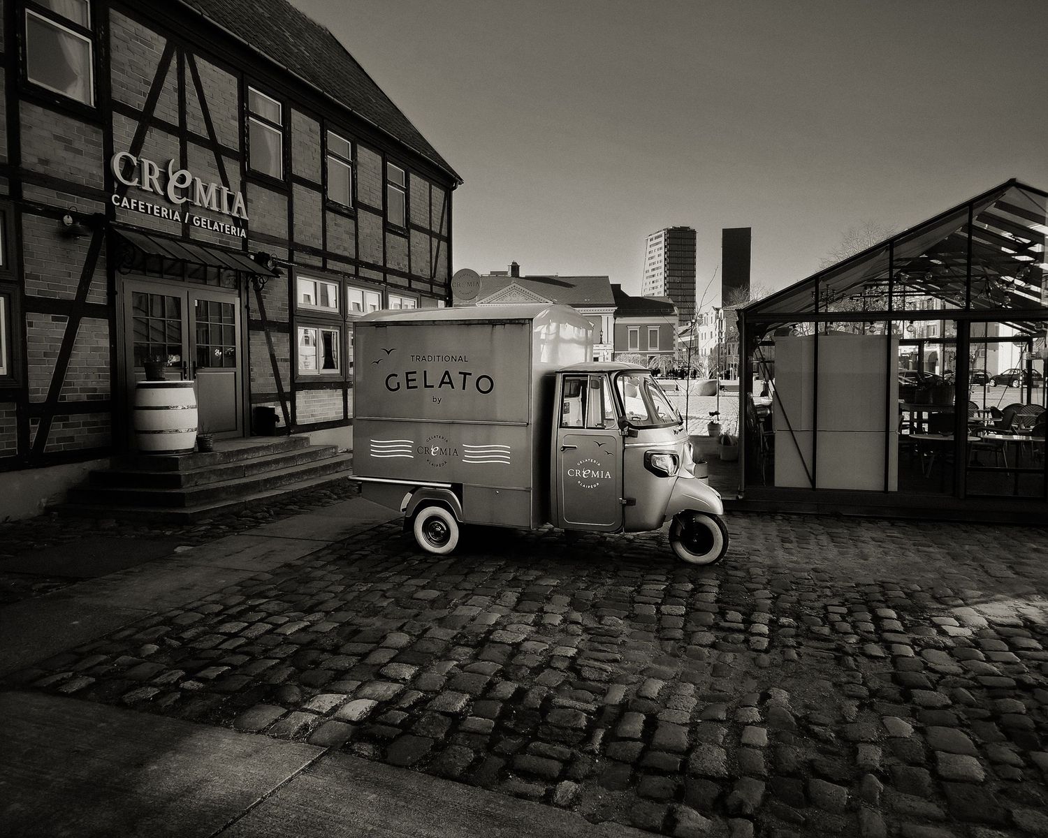 Vintage black and white sequence of a car driving through an industrial area with cobblestone streets.