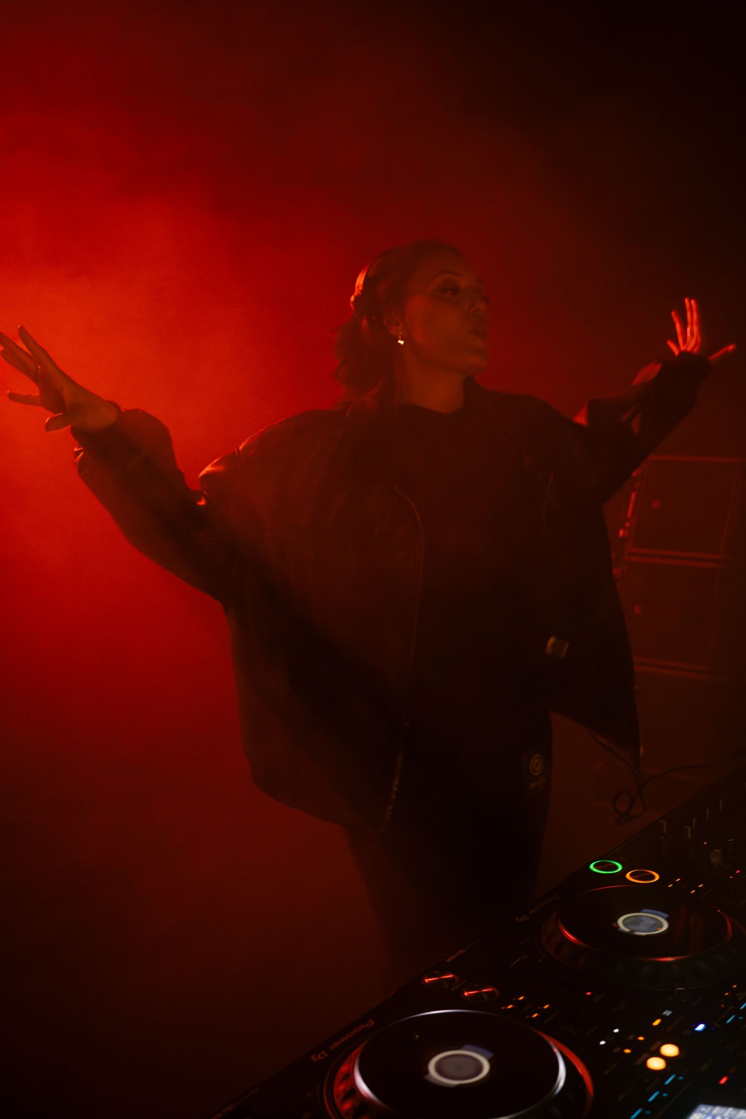 Silhouetted performers dancing in dramatic red stage lighting with fog effects create a theatrical atmosphere.