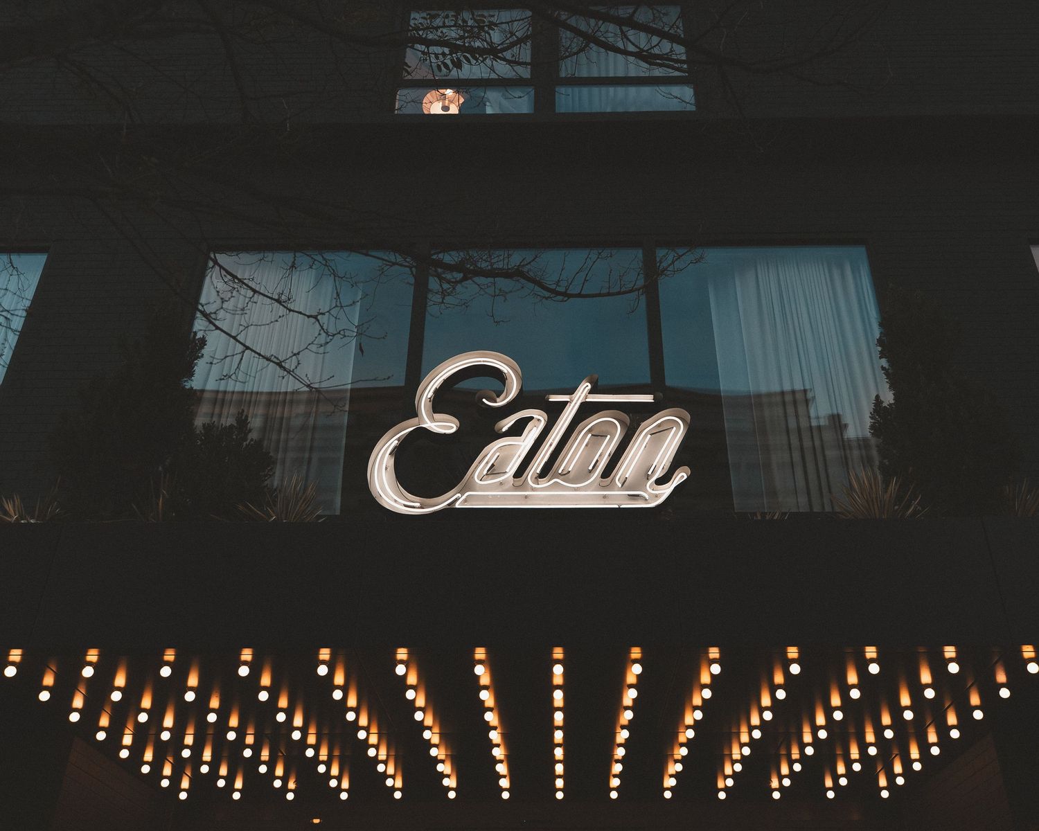 Row of illuminated light bulbs mounted along a dark exterior wall creating an atmospheric nighttime display.