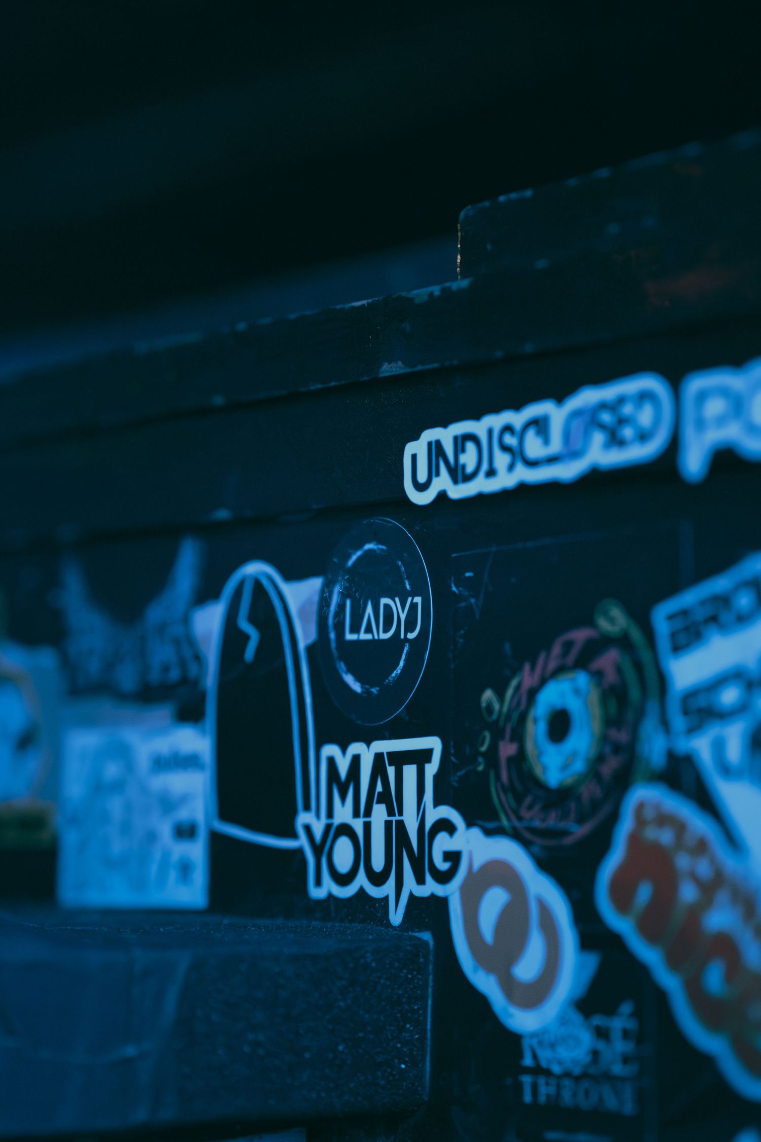 Graffiti art in neon blue tones decorates dark wall with urban street art style.