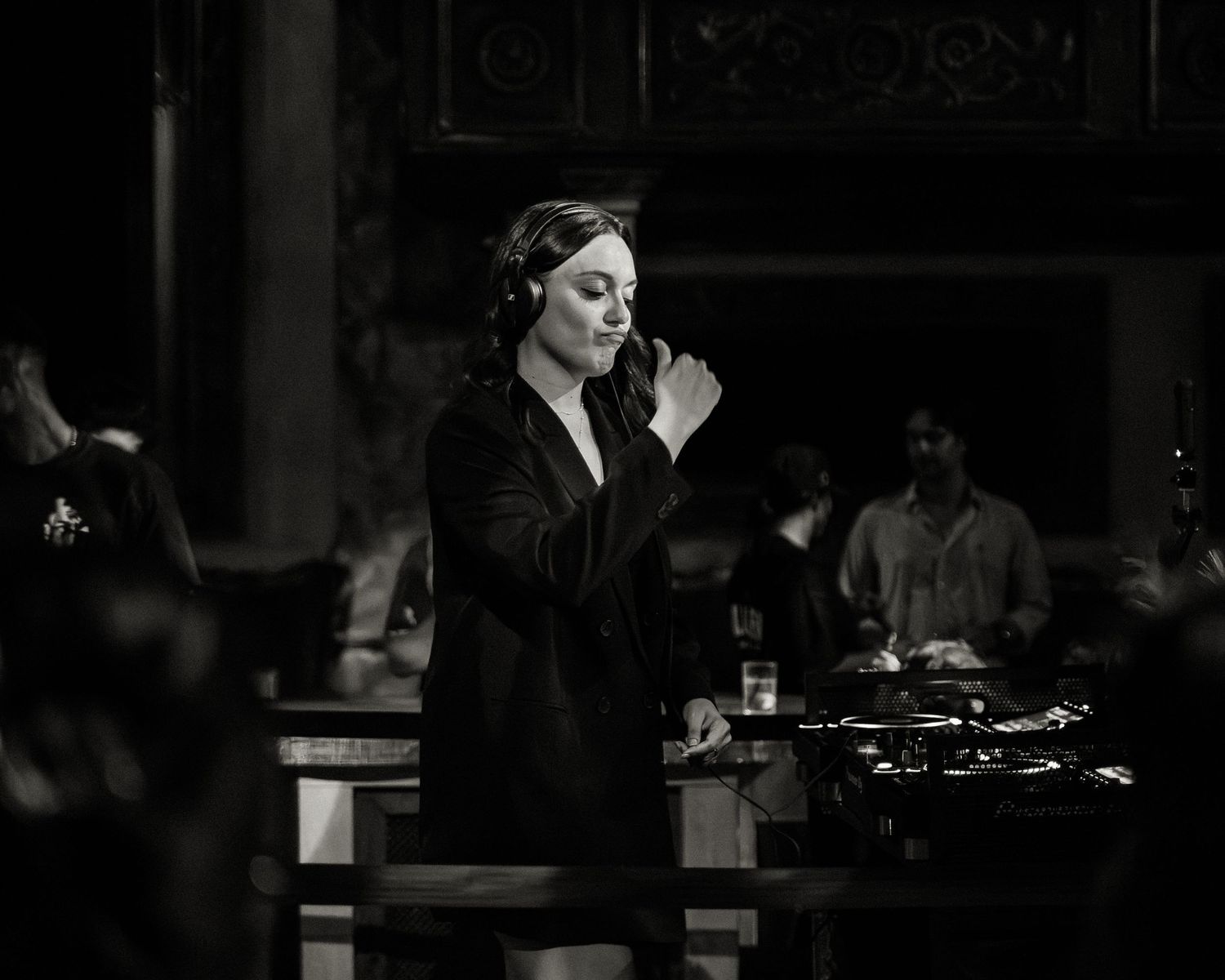 Dark monochrome image of performers in a moody bar setting.