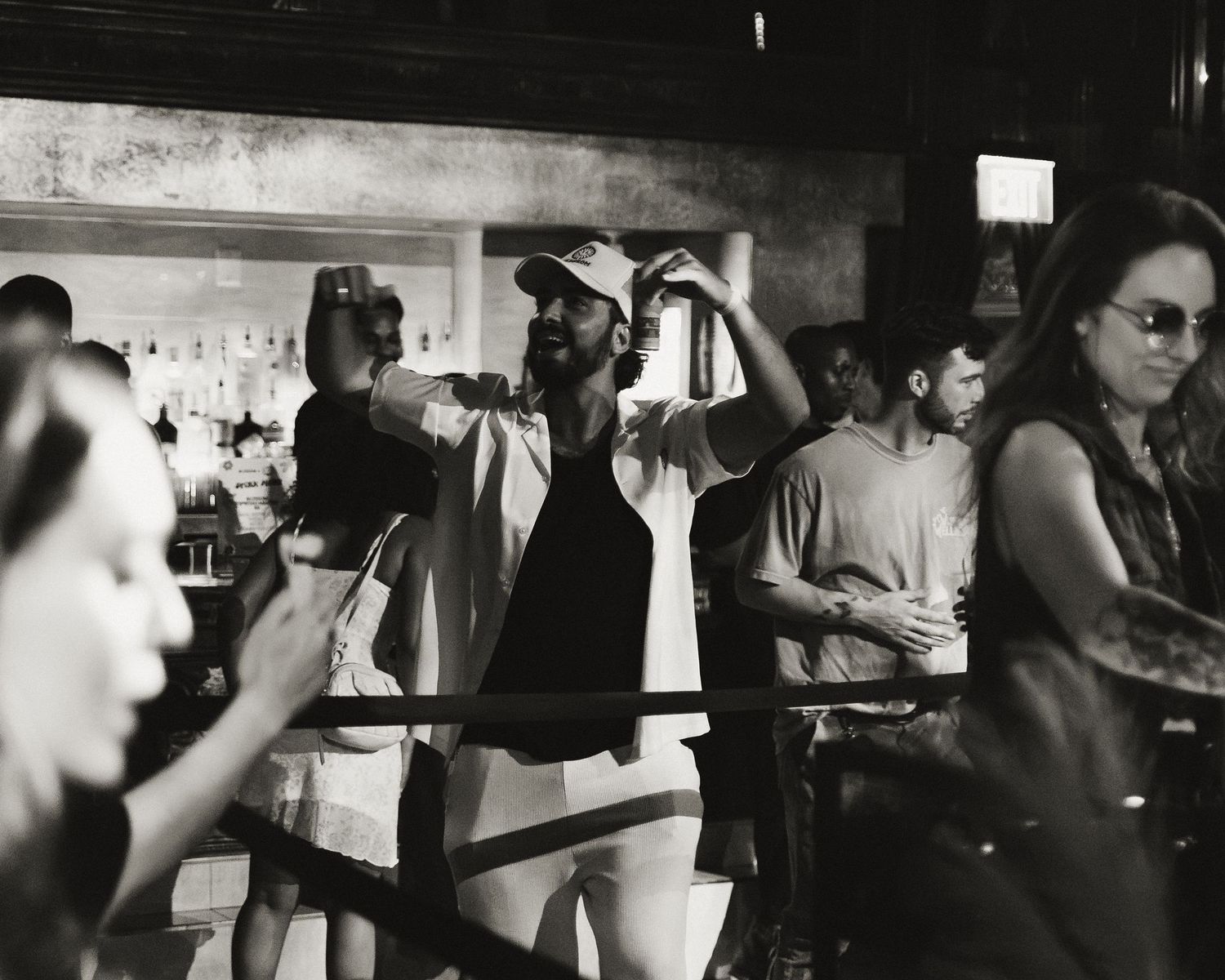 Crowd of people dancing and socializing at a bar with drinks.