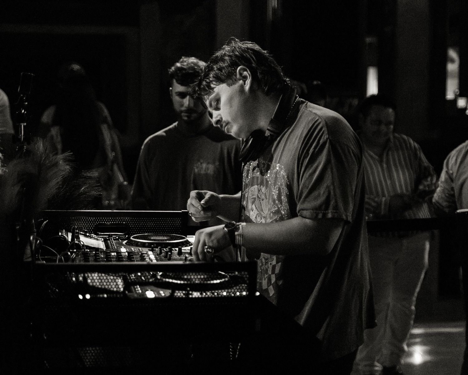 Dark nightclub interior with DJ equipment and crowd silhouettes.
