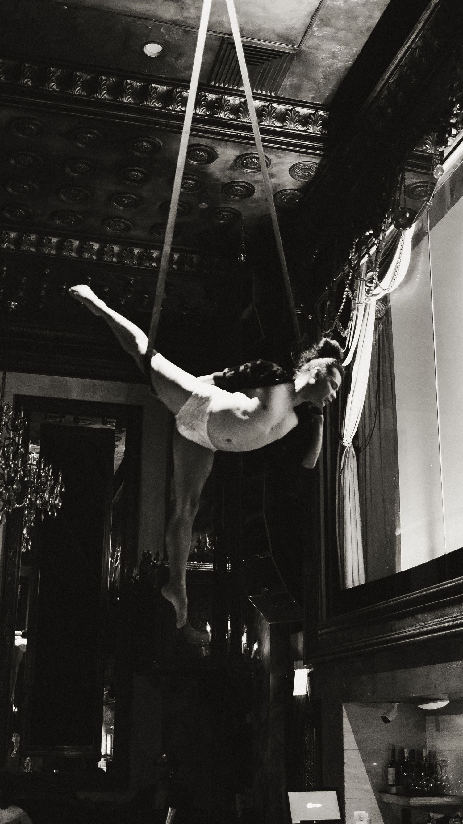 Aerial dancers performing graceful moves on suspended equipment in a theatrical space.