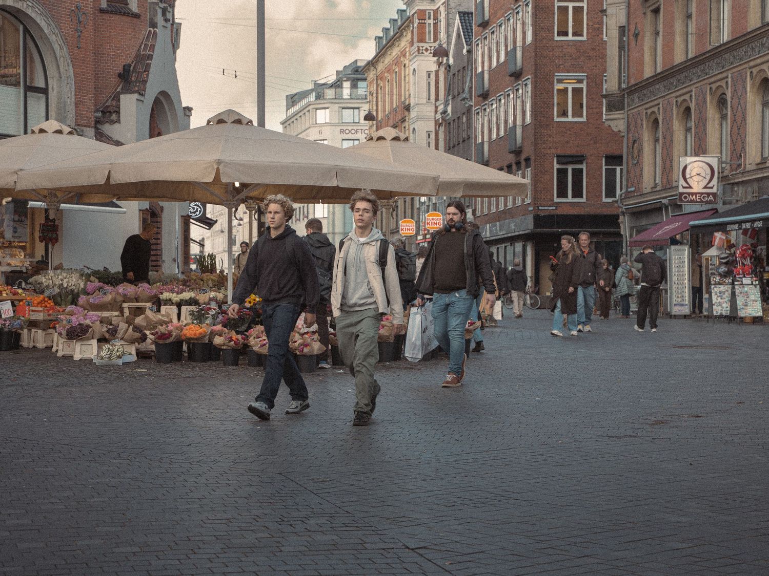 Urban street scene showing pedestrians walking through a historic European town square.
