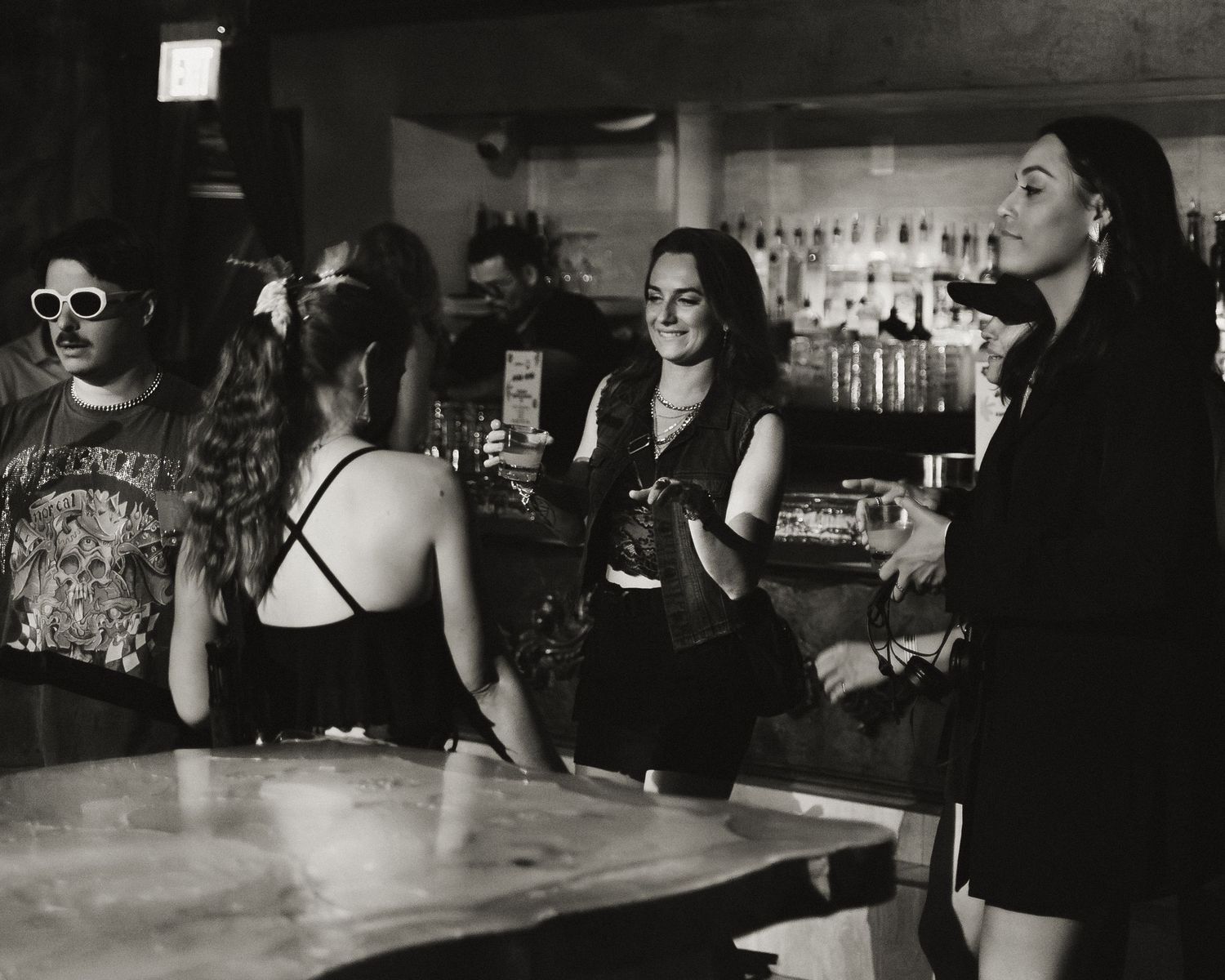 People seated at a bar counter in a dimly lit nightclub atmosphere.