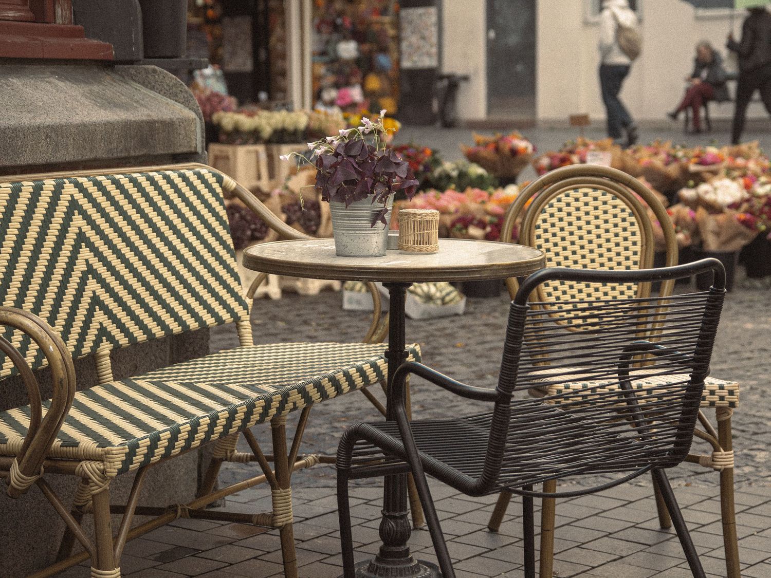 Row of bistro-style chairs and tables arranged outside a cafe with decorative elements.