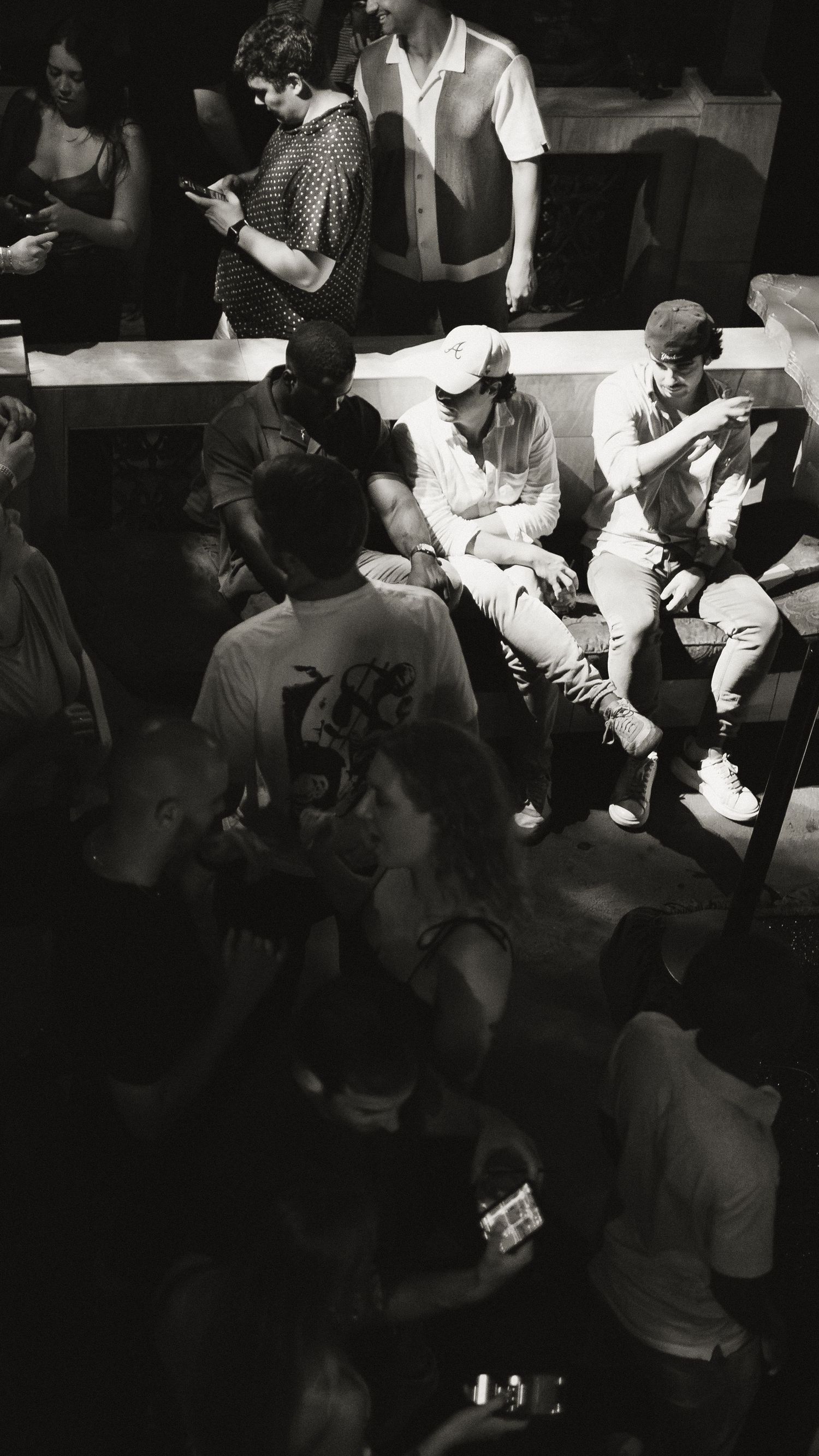 Crowded nightclub scene with people gathered in dark atmospheric lighting.