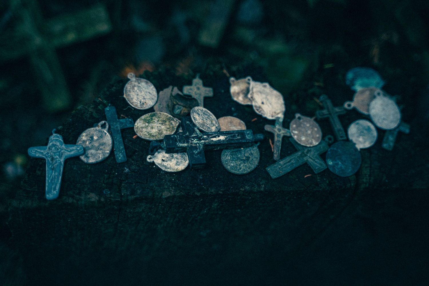 Weathered religious artifacts and crosses scattered in low light conditions.