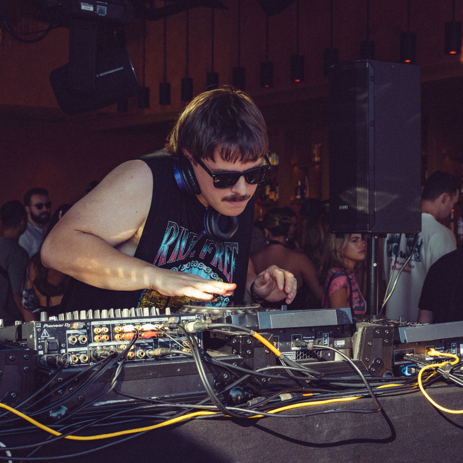 Close-up of DJ equipment and mixing board in a dark club setting.