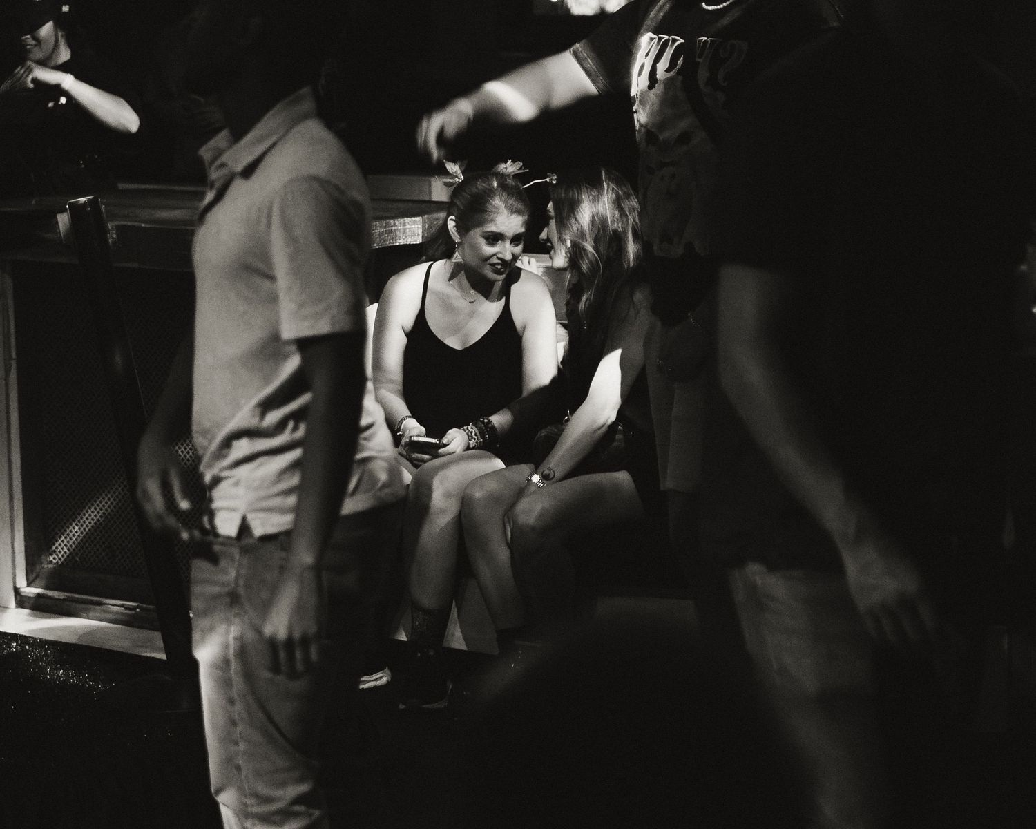 Dark atmospheric scene showing movement and interaction between performers in a dimly lit space.