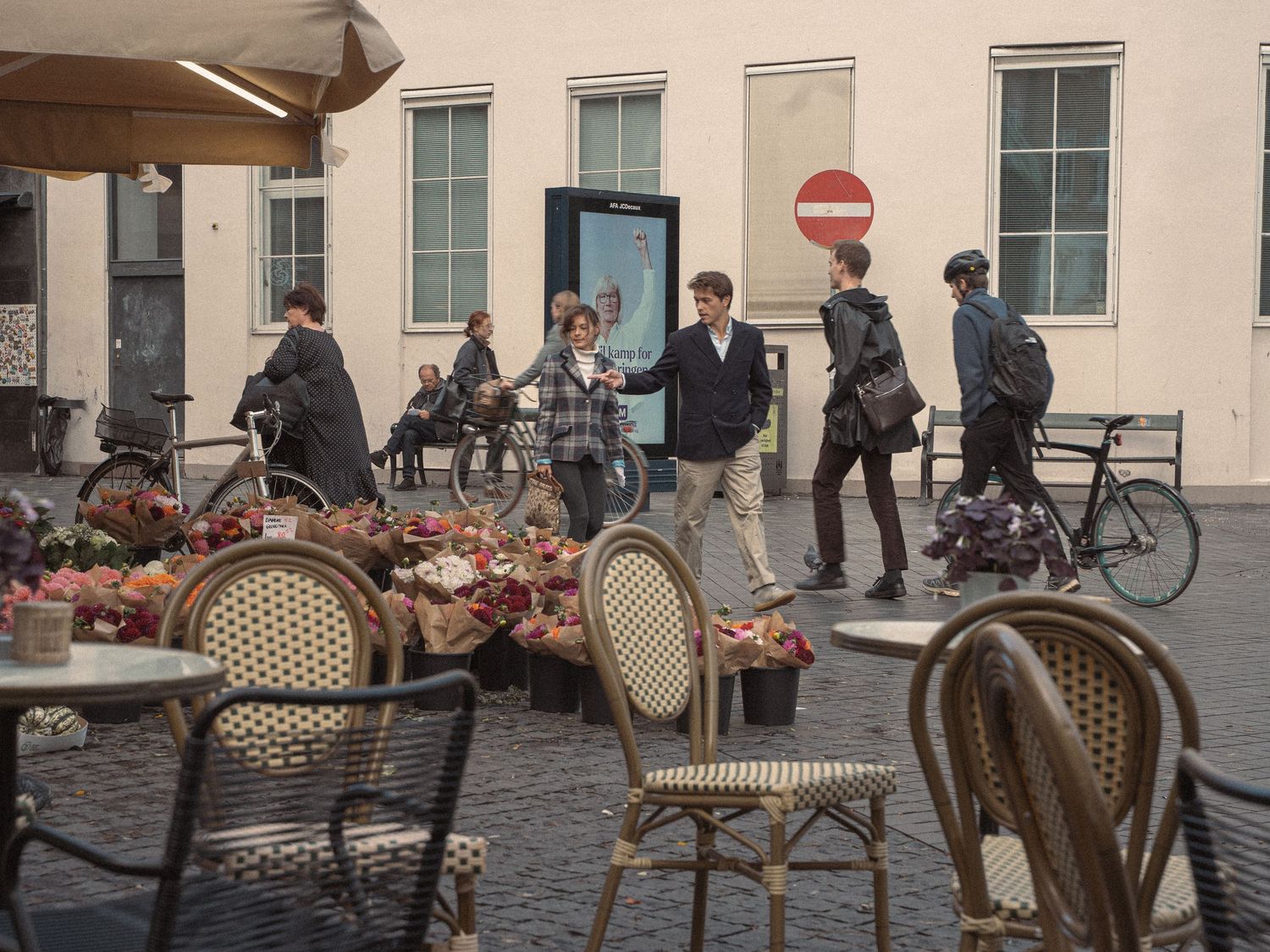 Outdoor cafe seating with woven chairs arranged along a building facade.