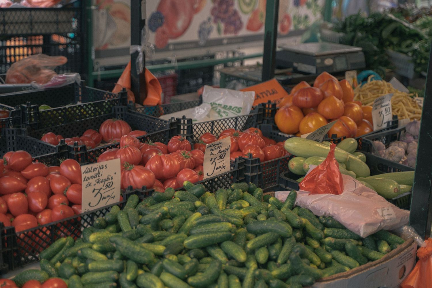 Colorful produce display featuring tomatoes, cucumbers and other fresh vegetables at market.