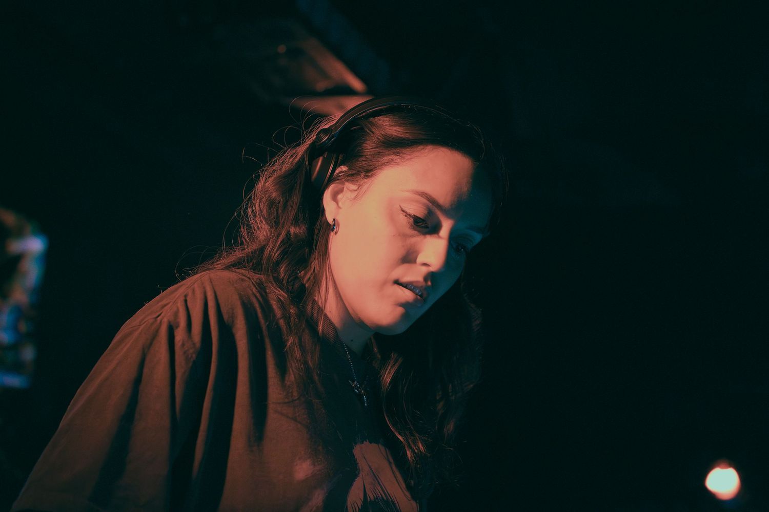 Dimly lit performance scene with dramatic shadows and deep blue tones creating a mysterious ambiance.