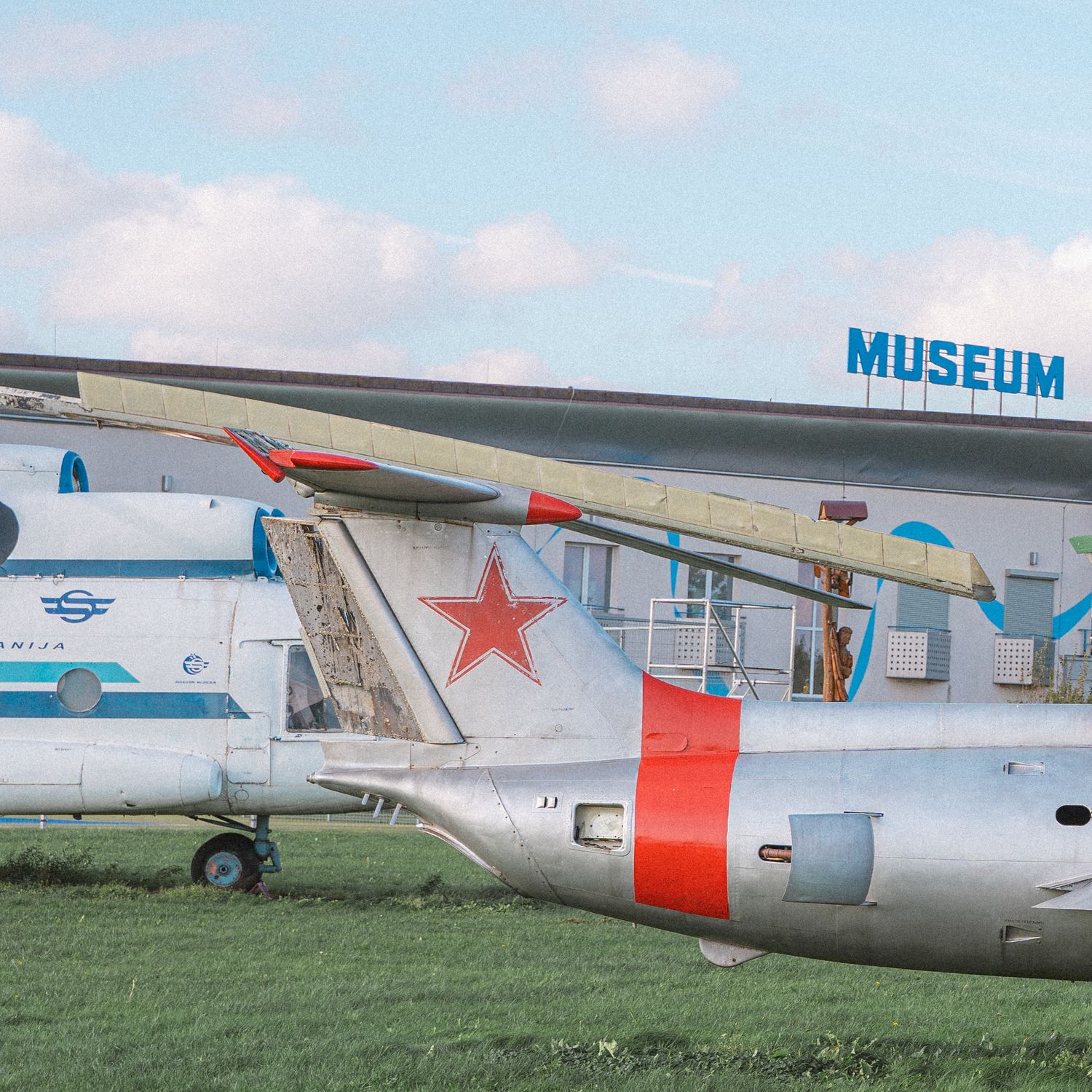 Vintage aircraft with red star marking displayed outside aviation museum.