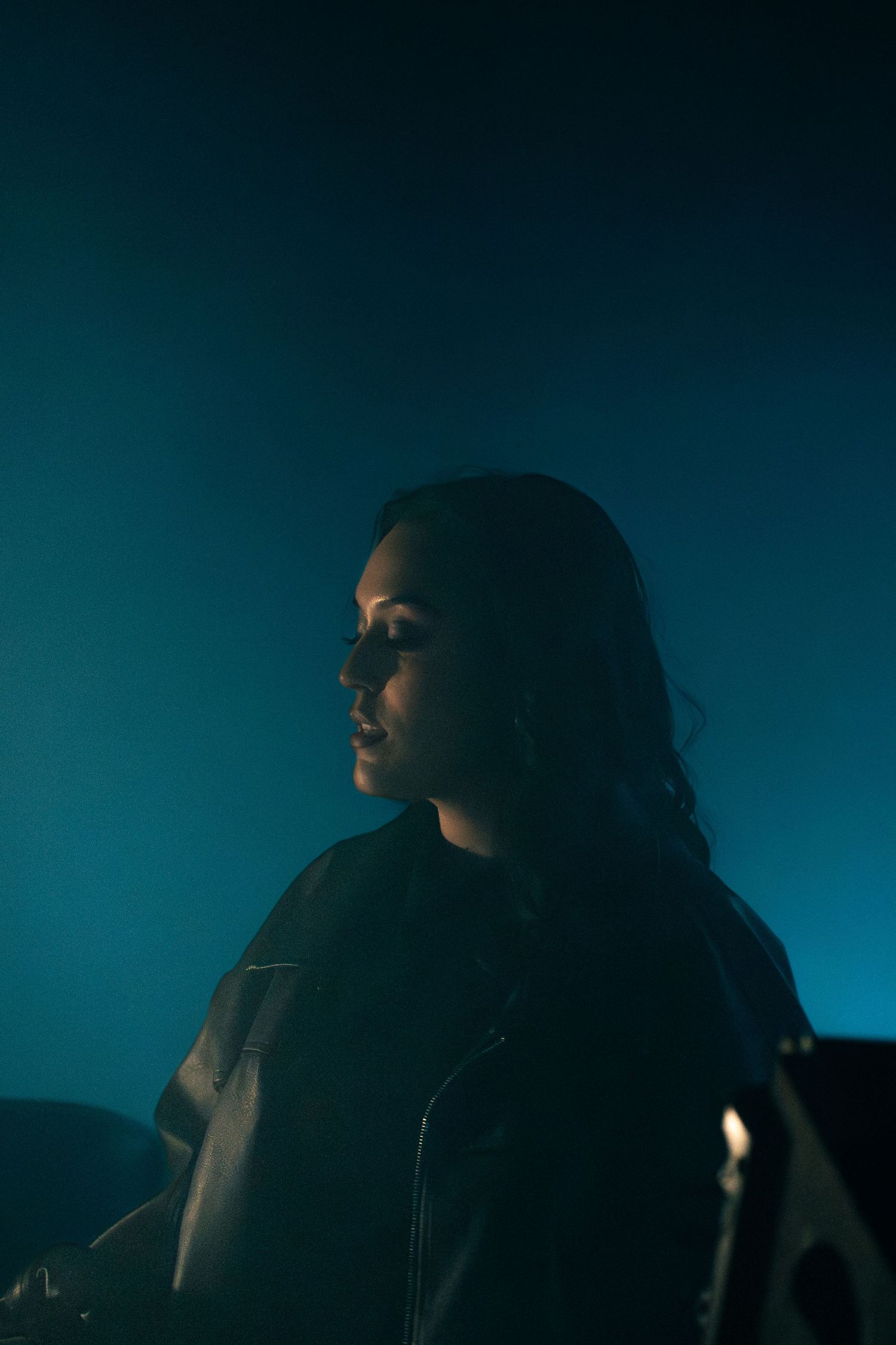 Dramatic silhouette portrait against dark blue background with moody lighting and shadow effects.