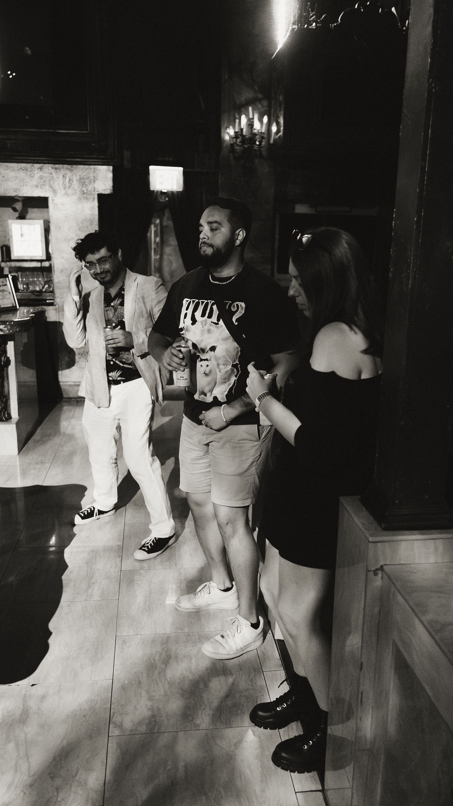 People dancing in a dimly lit club with dramatic shadows and light.