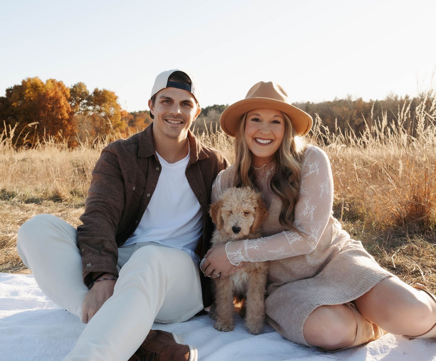 Family relaxing outdoors with their fluffy dog in a sunny field.