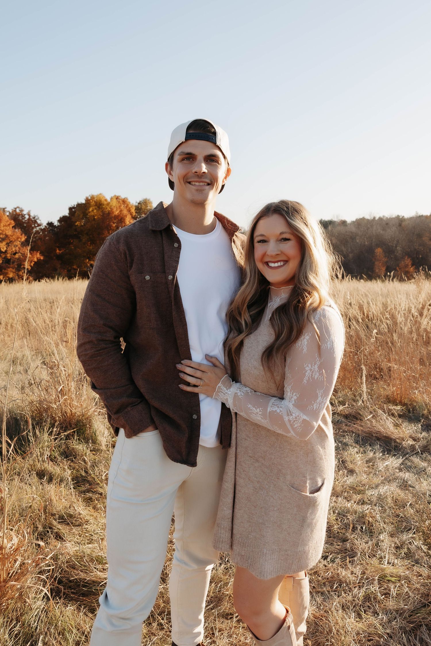 Happy couple in coordinated outfits enjoying a sunny day in a field.