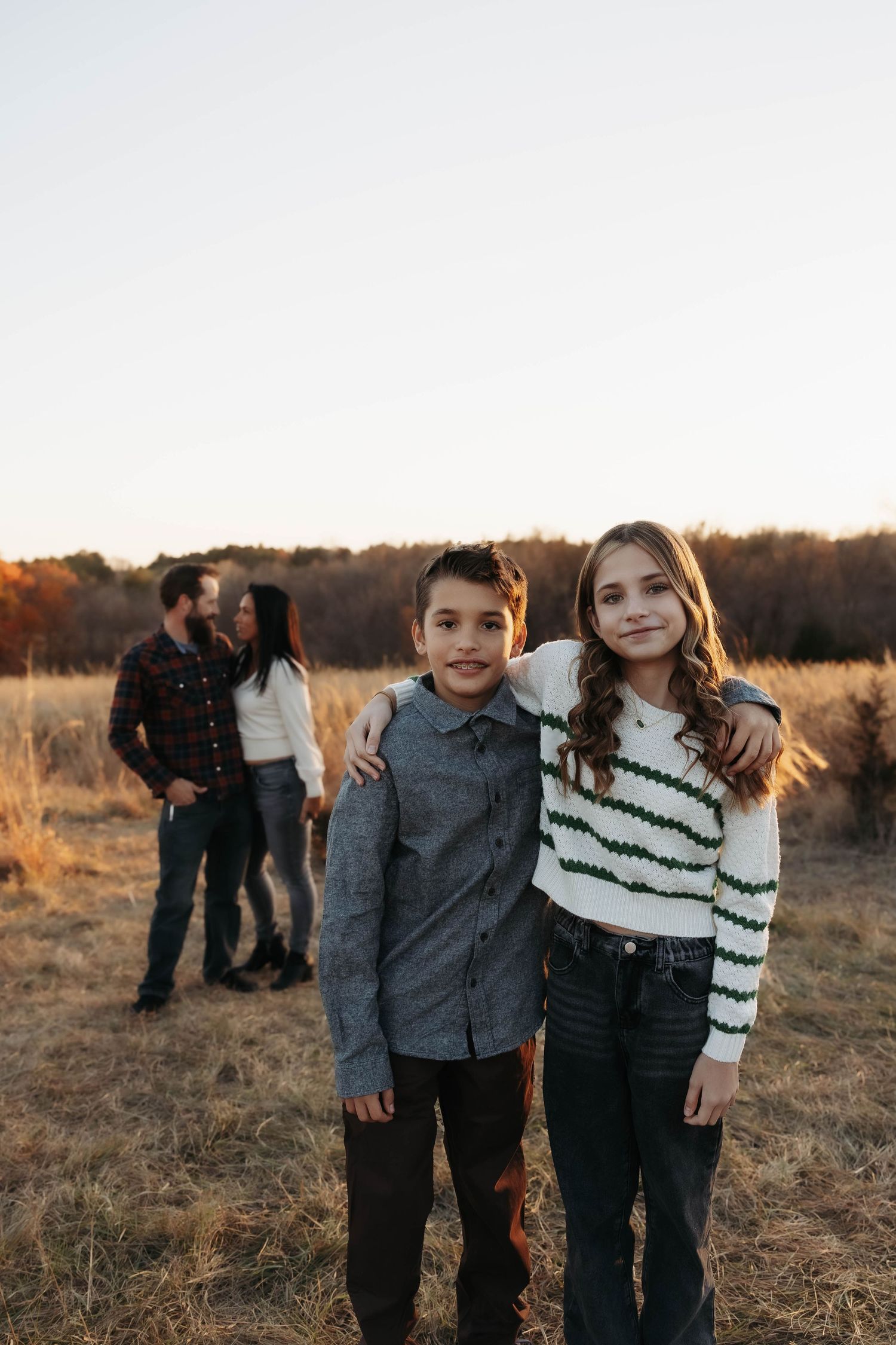 Children standing together in casual wear against autumn field backdrop.
