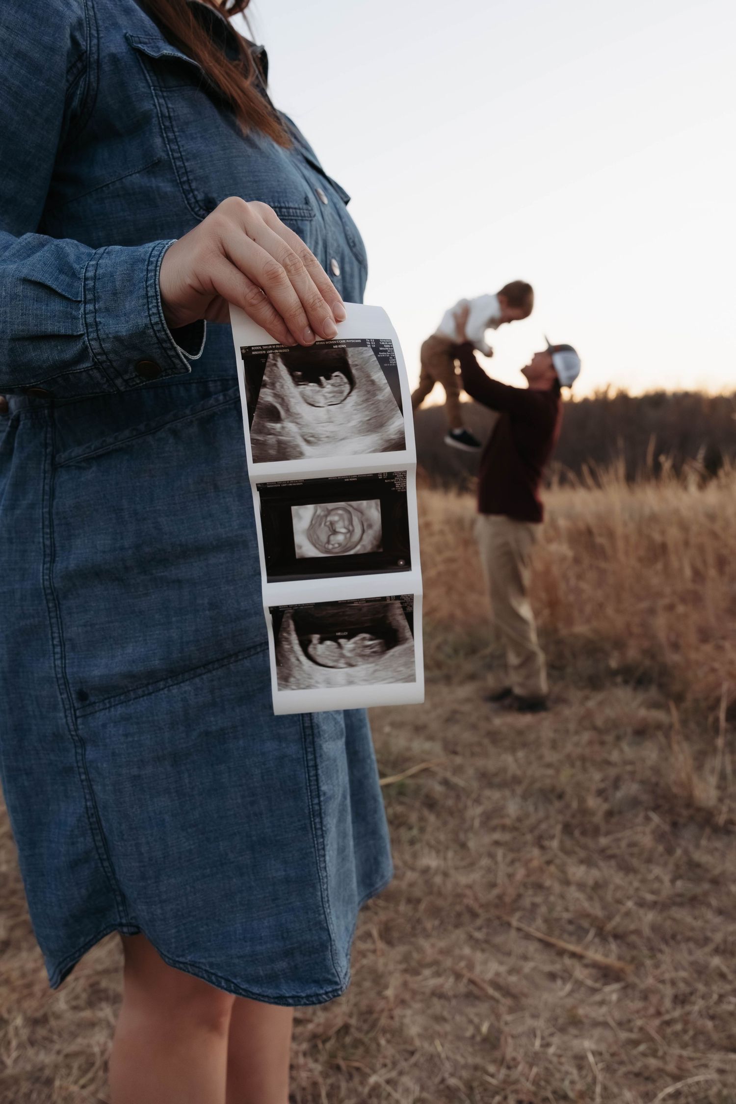 Person holding ultrasound photos in a field during golden hour.
