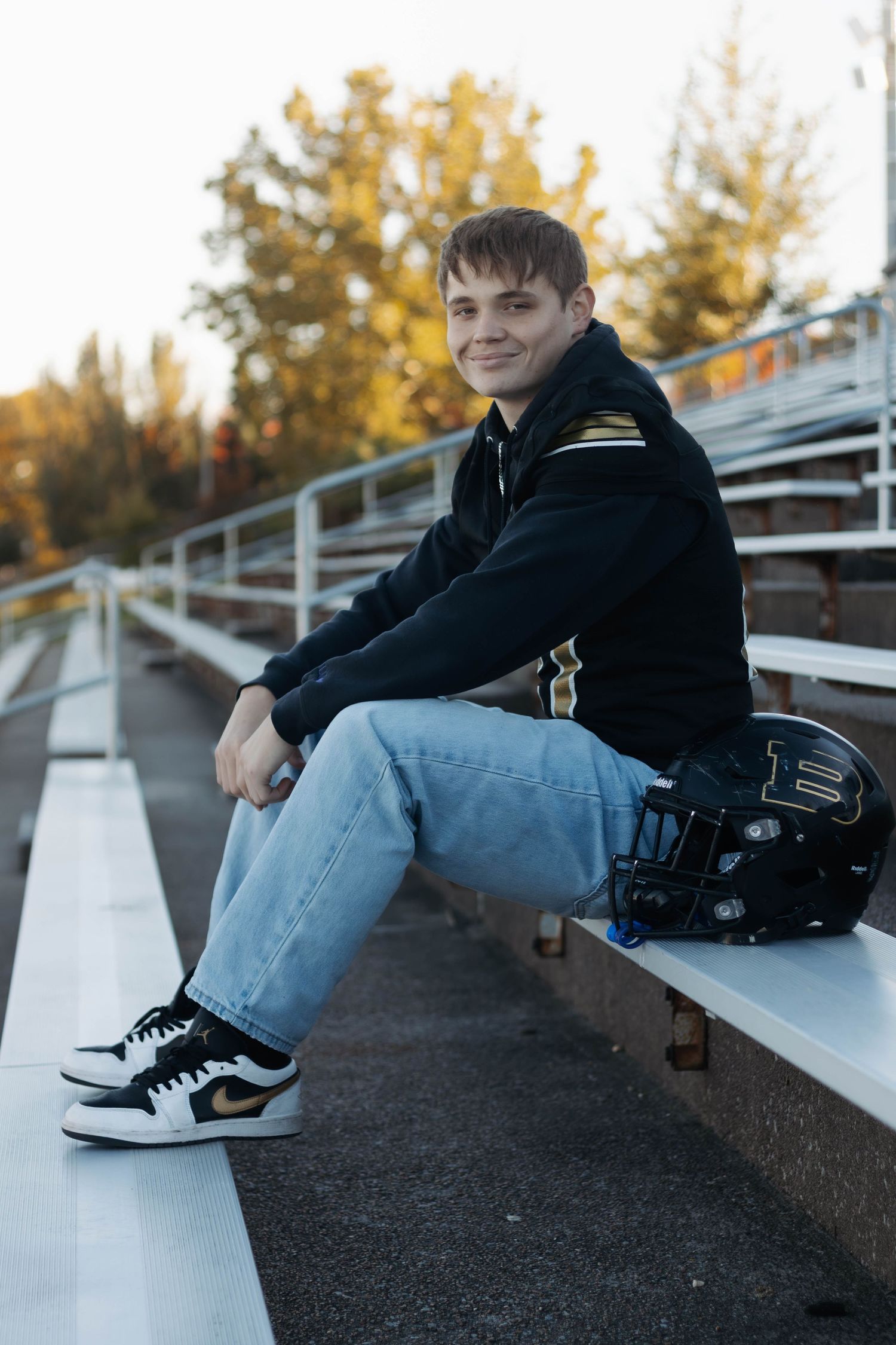 Person in black jacket sitting casually on outdoor bleachers.