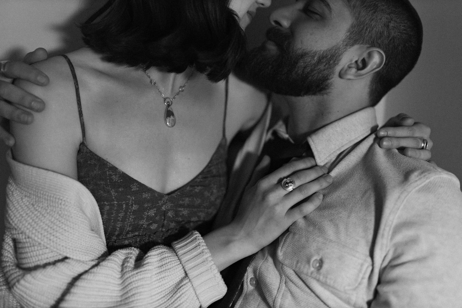 Couple embracing tenderly in black and white photo, man kissing womans temple softly.