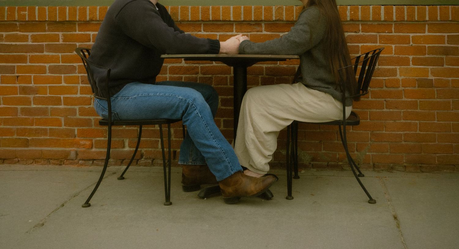 Two people sit and chat on a patio bench against a brick wall in a series of progressive frames.