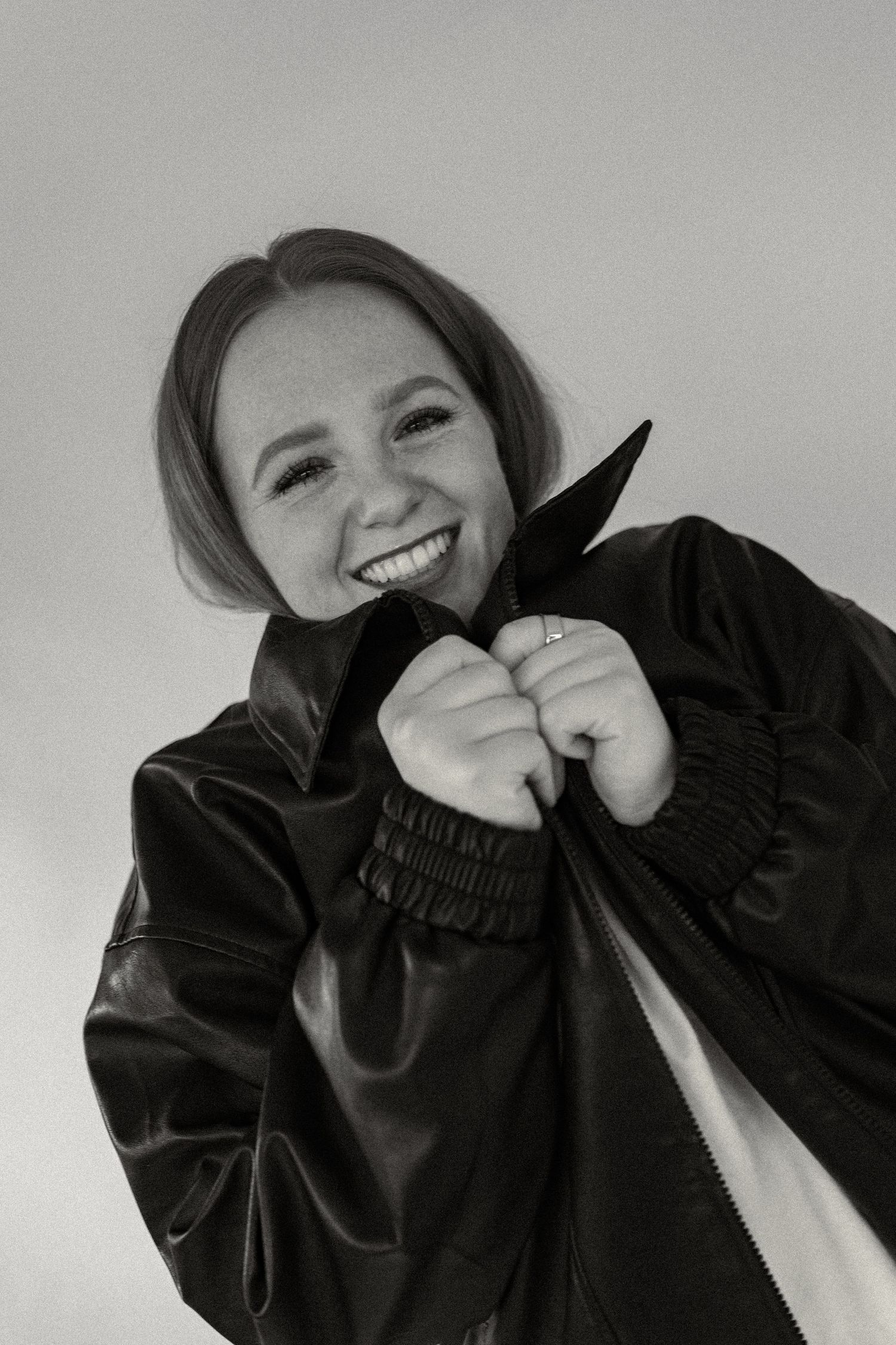 A sequence of black and white photos showing someone in a black sweater expressing joyful emotions against a light background.