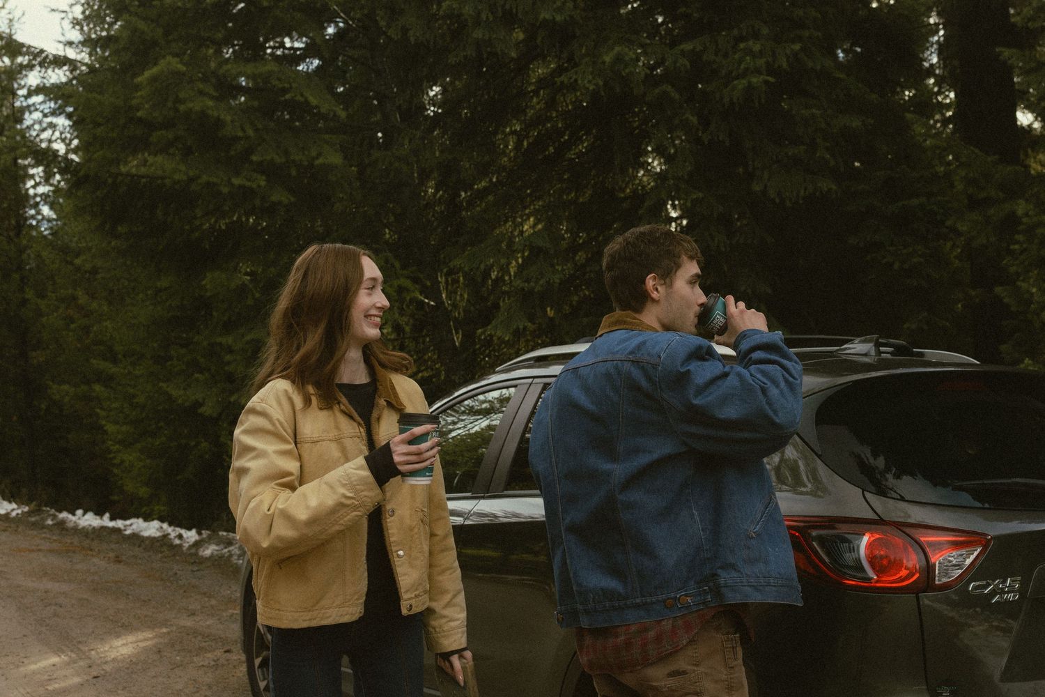 Two people in casual outerwear walk together through a parking lot on an autumn day.