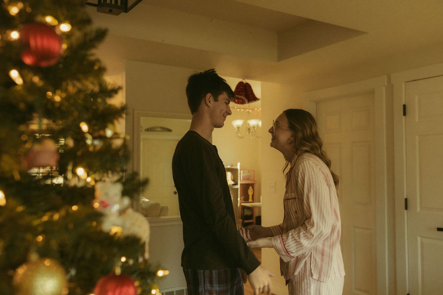 A couple shares a romantic dance in their living room decorated with a glowing Christmas tree and holiday lights.