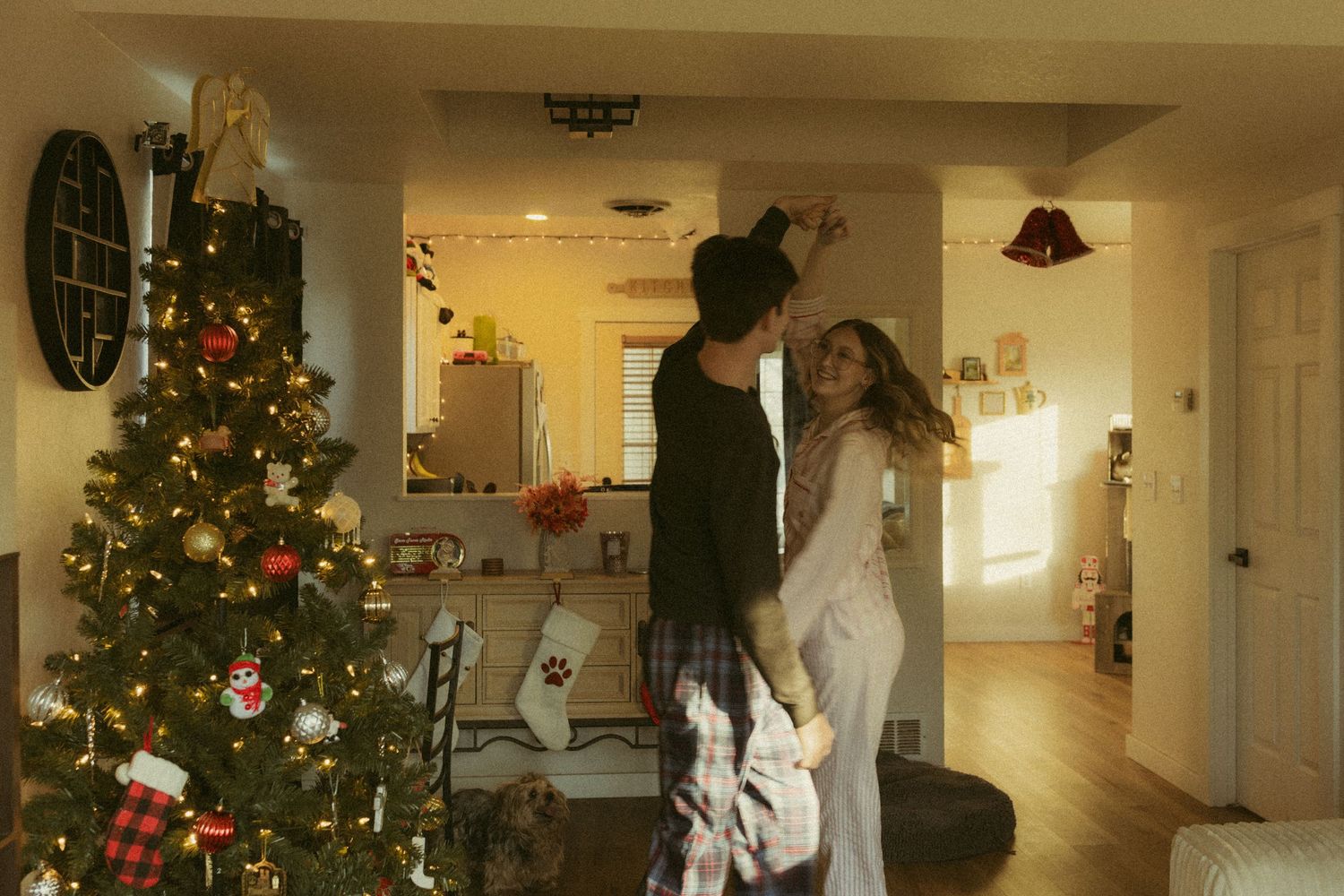 A festive hallway decorated with multiple Christmas trees, lights, and holiday decorations creating a warm atmosphere.