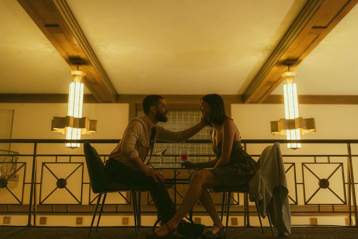 Couple sharing an intimate moment at a candlelit restaurant table in warm golden lighting.