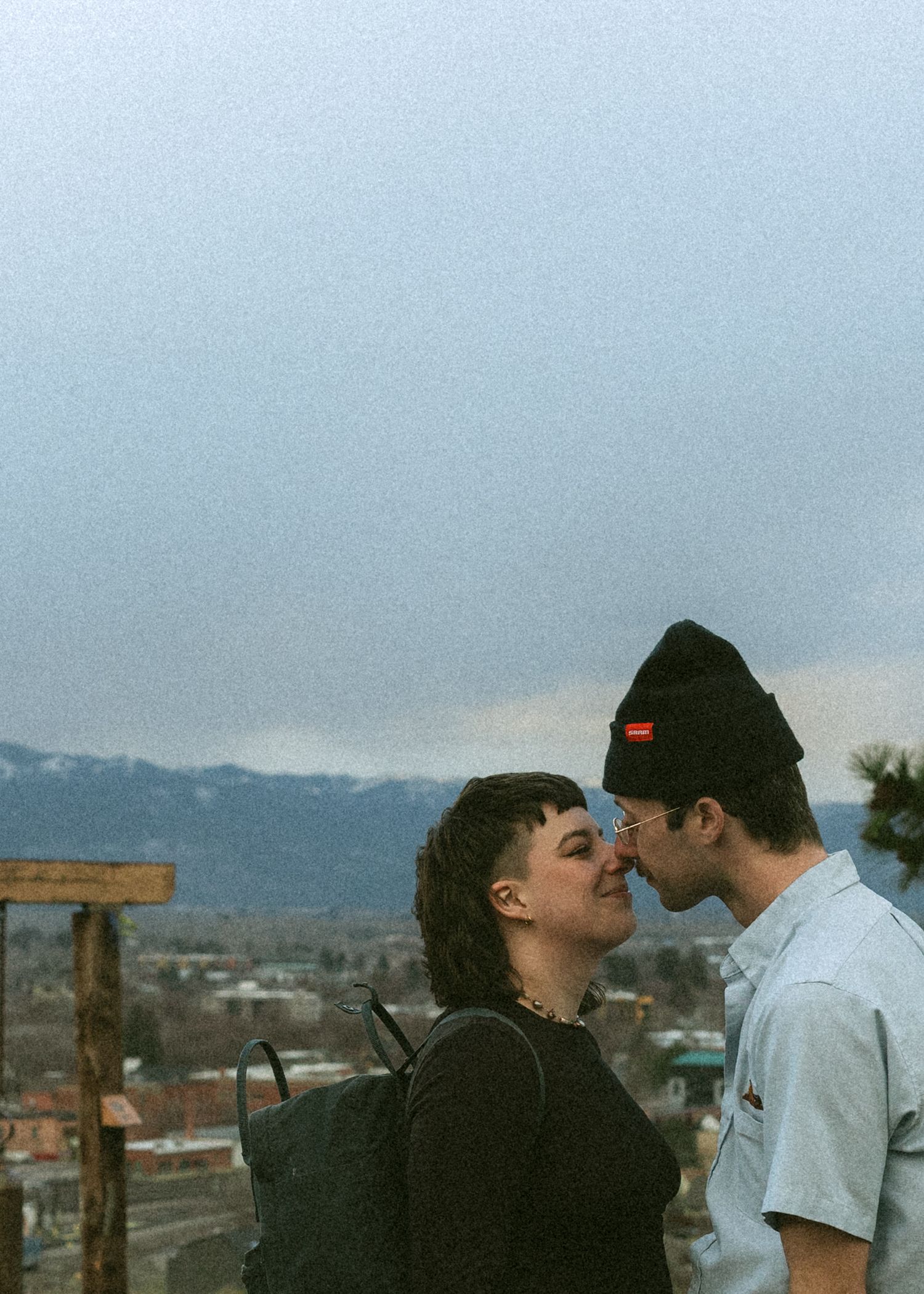 A couple shares an intimate moment together on a foggy day with mountains visible in the background.