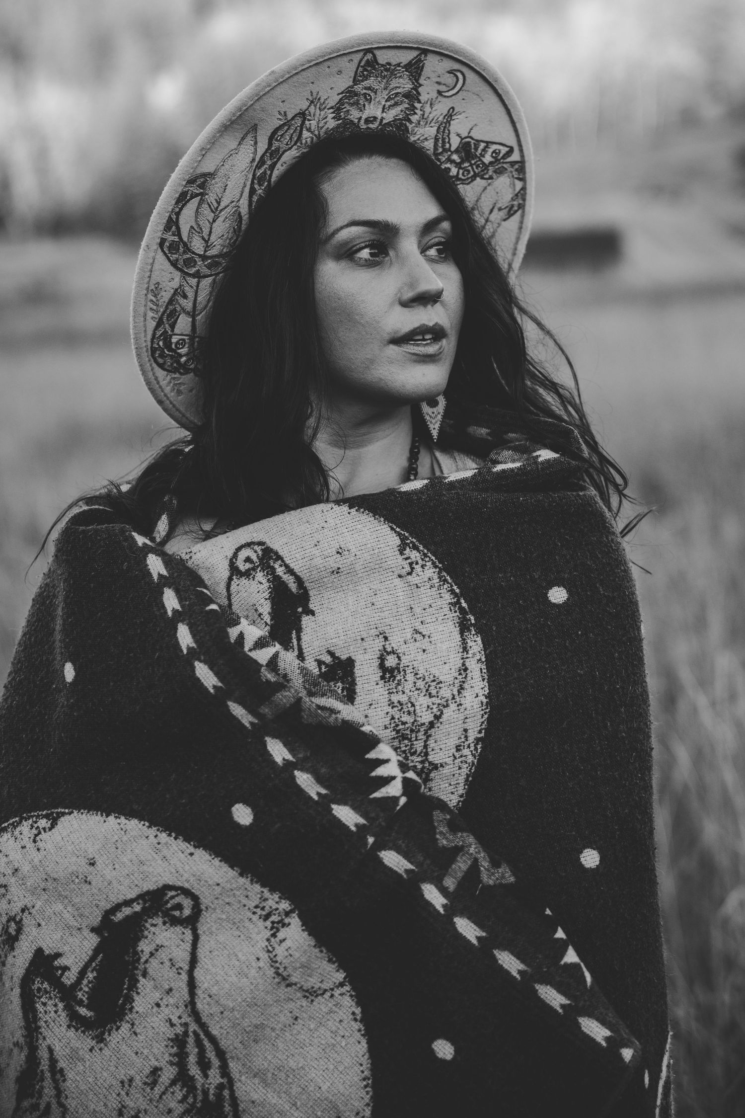 Black and white portrait with vintage-style hat and scarf in dramatic lighting.