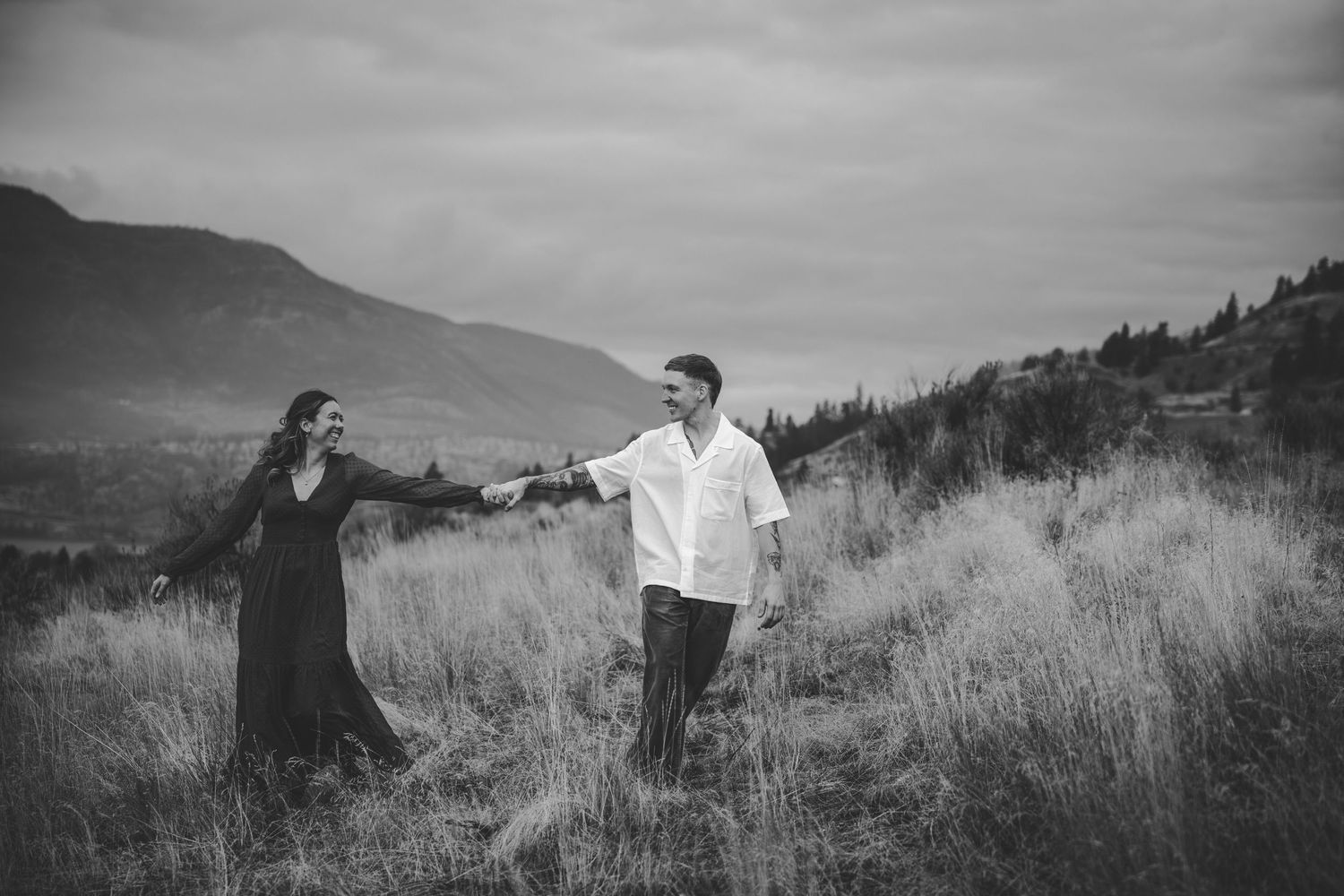 A black and white landscape photo showing two figures in a grassy hillside setting.