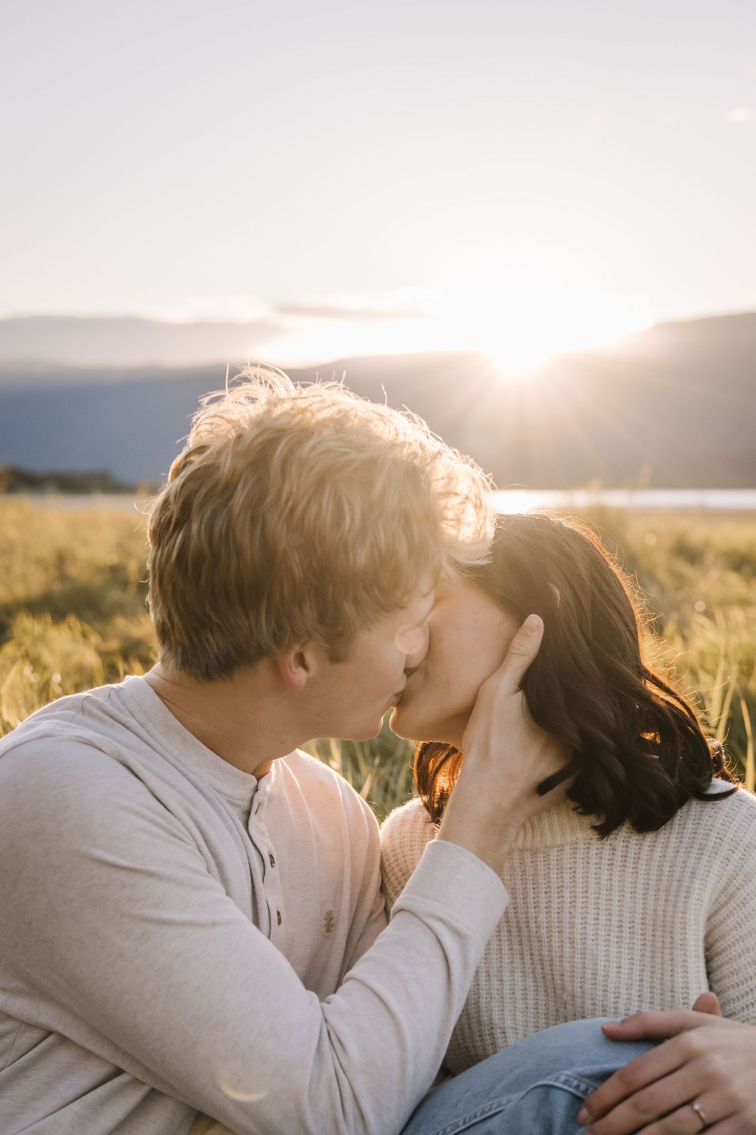 Couple sharing tender moments in a sunlit field during golden hour.
