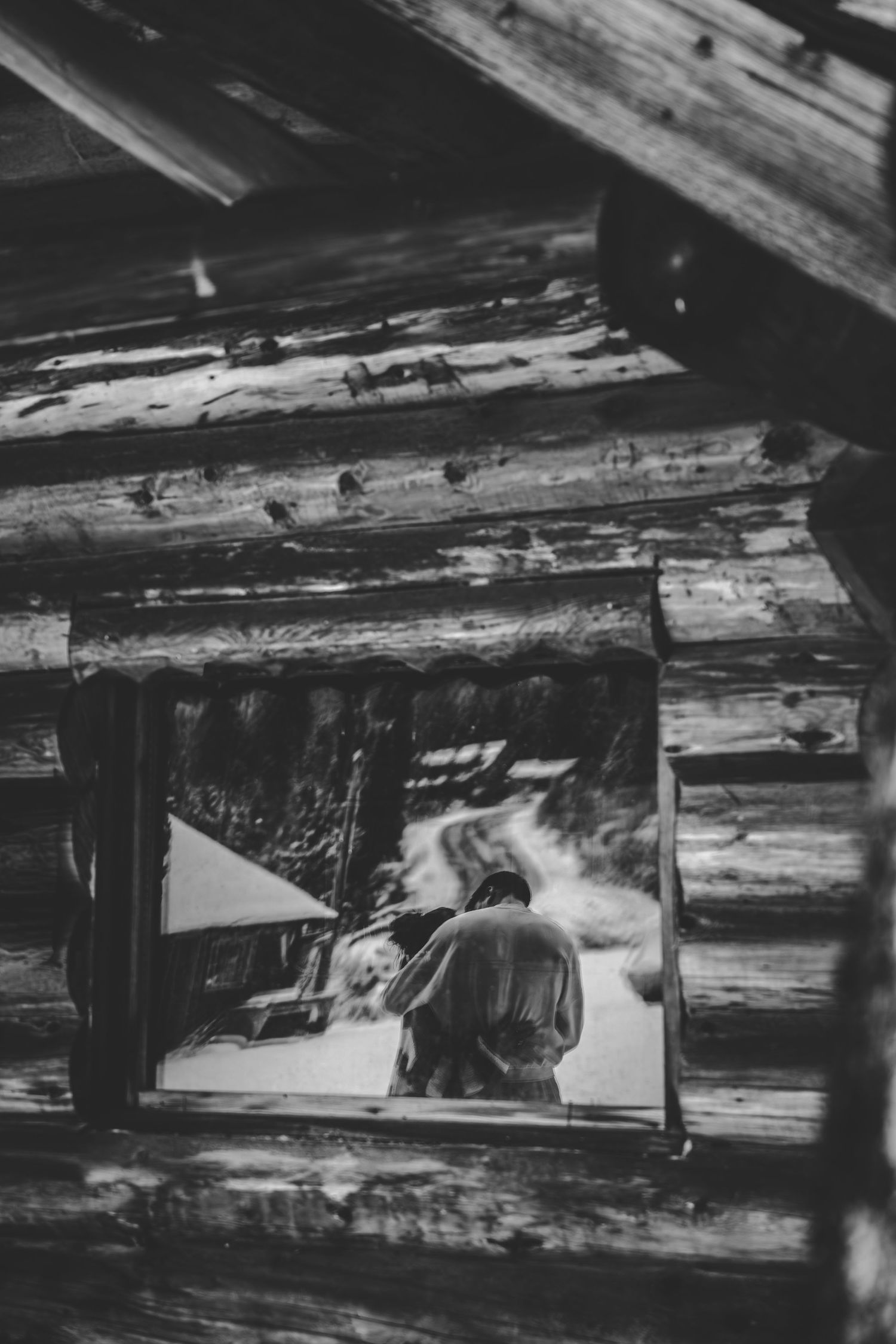 Interior view of rustic wooden cabin beams and ceiling in black and white.