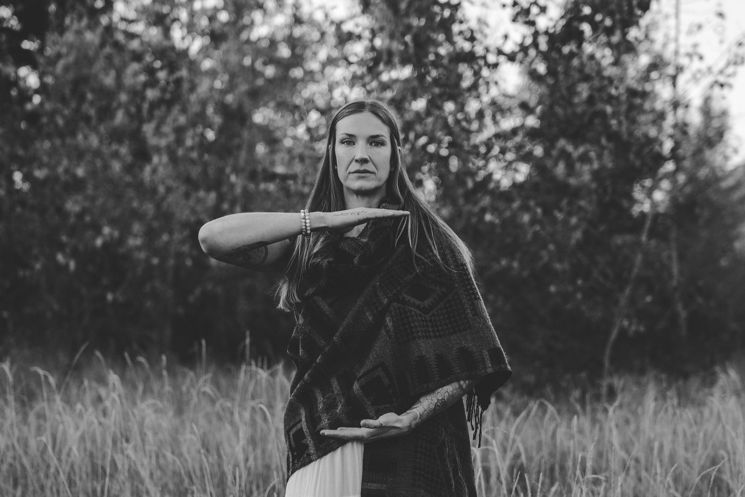 Black and white portrait session in tall grass with dramatic composition.