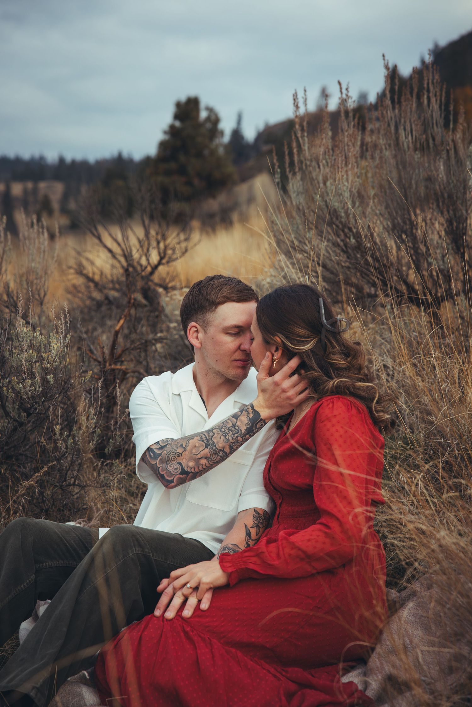 A tender moment shared between two people in a field of dried grass.