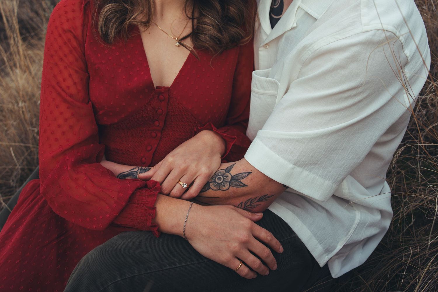 Intimate close-up showing hands and clothing details in an outdoor setting.