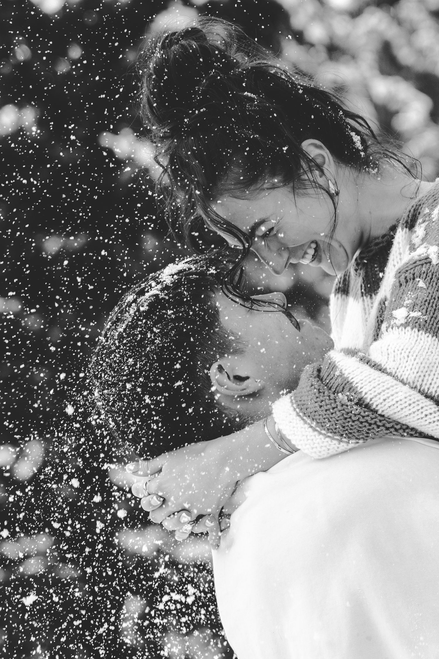 Black and white winter portrait with falling snow and soft bokeh effects.